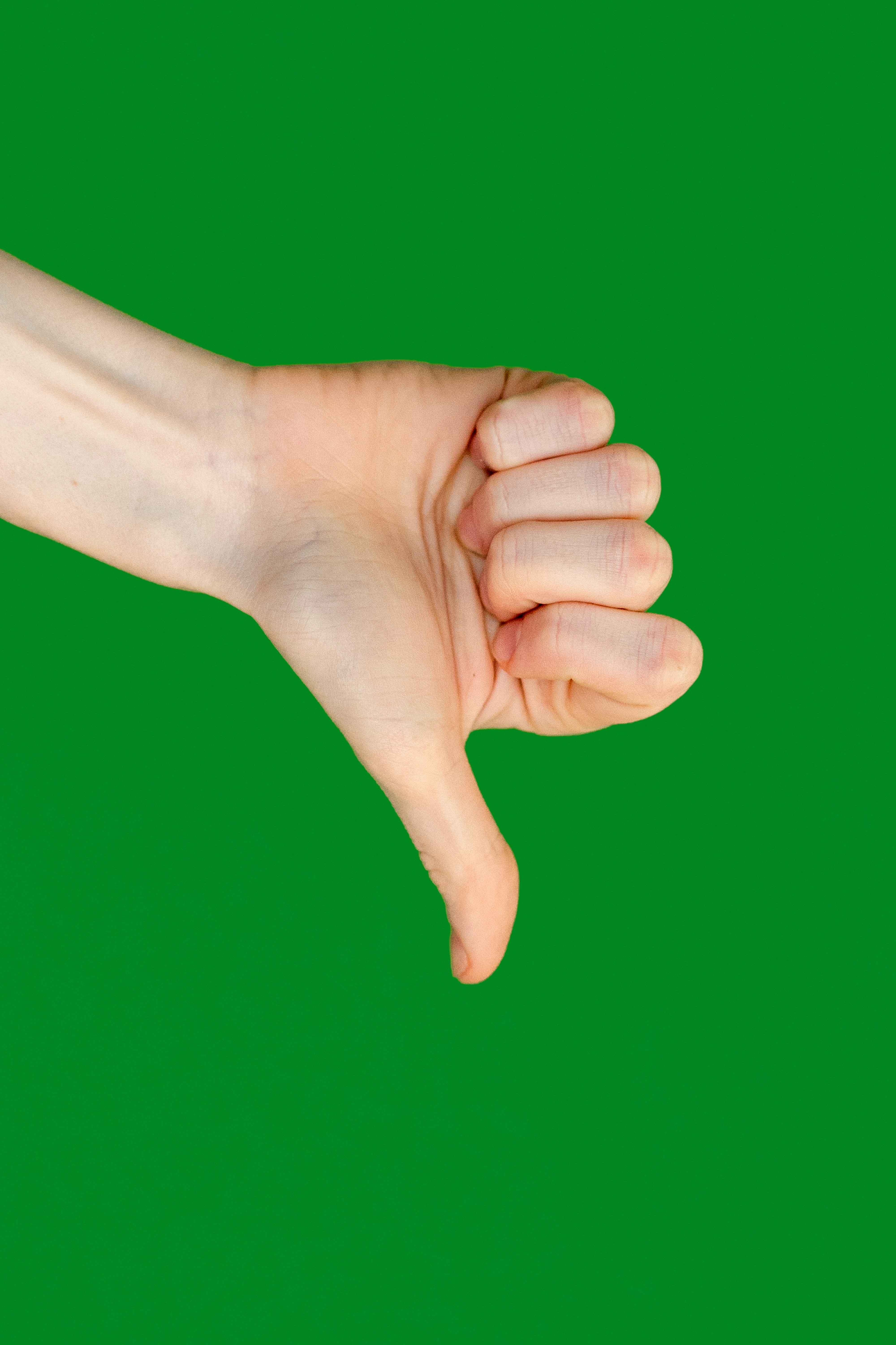 Thumbs down hand on green background.